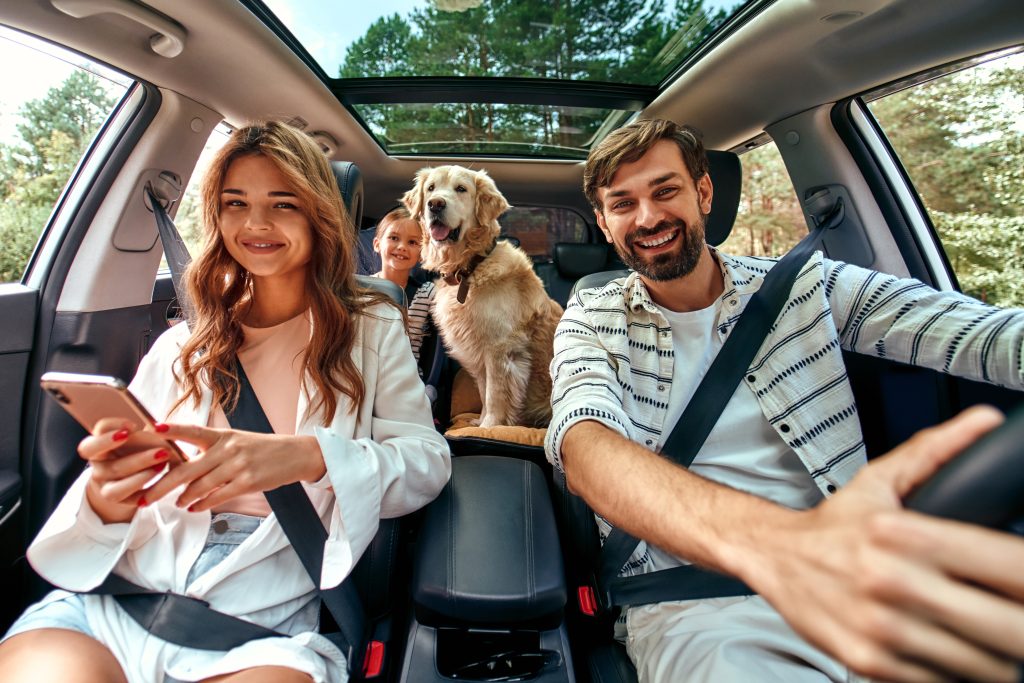 mladá štastná rodina cestuje v aute na víkend spolu so svojim psom